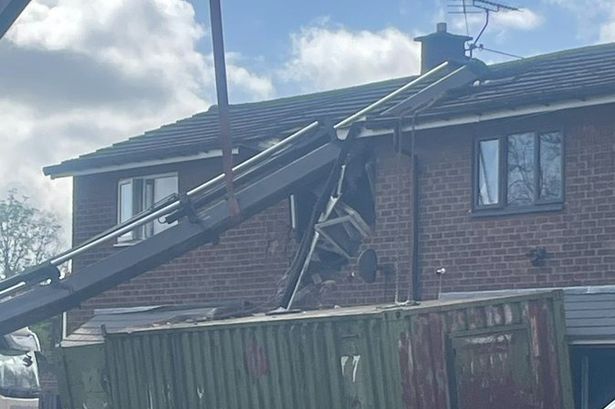 Crane topples into house as emergency services rush to scene and road closed