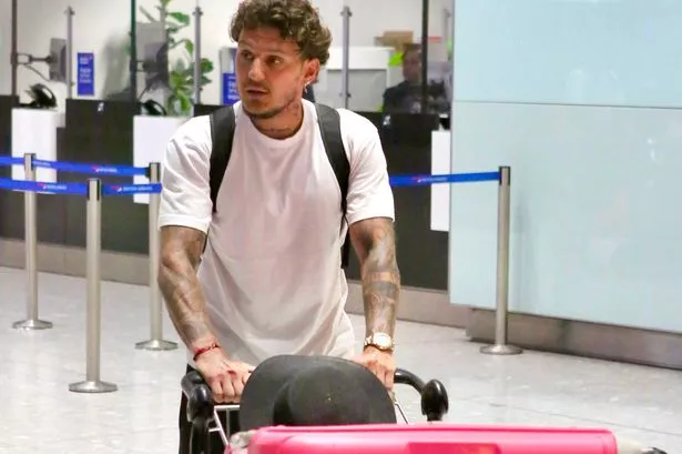 Katie Price’s boyfriend JJ Slater cuts a lonely figure as he’s seen pushing pink cases after her arrest at Heathrow airport