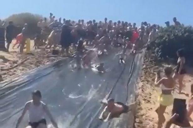 Crowds flock to makeshift beach waterslide as sun beats down